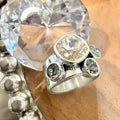 A silver-toned statement ring with a large cushion-cut champagne center Swarovski crystal and three smaller oval clear stones.